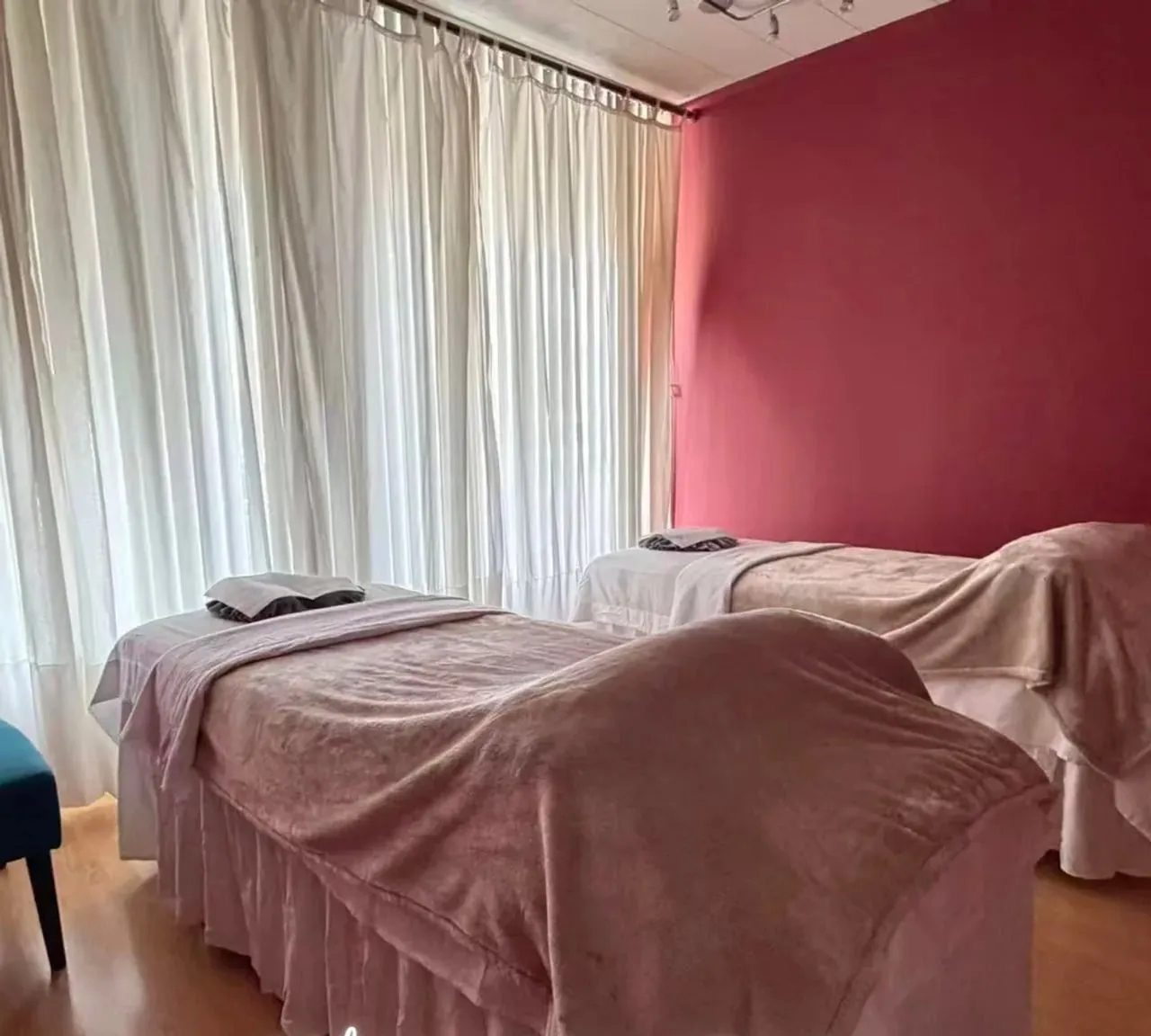 Couples room at Organic Day Spa, two massage tables made up side by side against a rose wall
