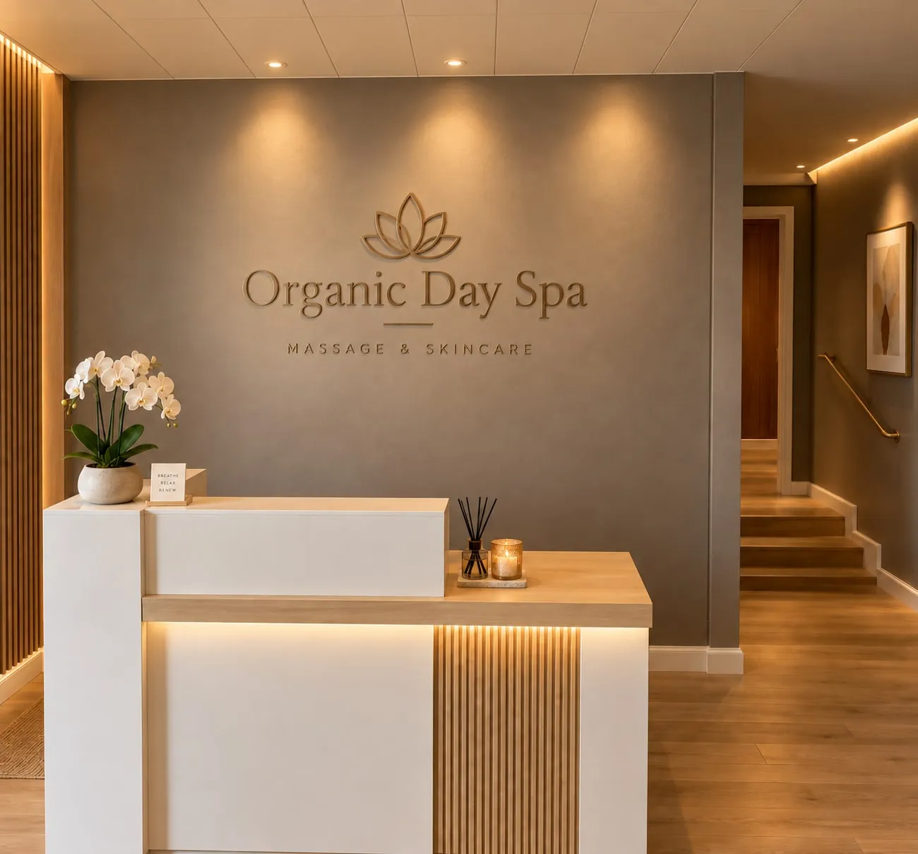 The Organic Day Spa reception desk, with orchids, a lit candle and the hallway to the treatment rooms