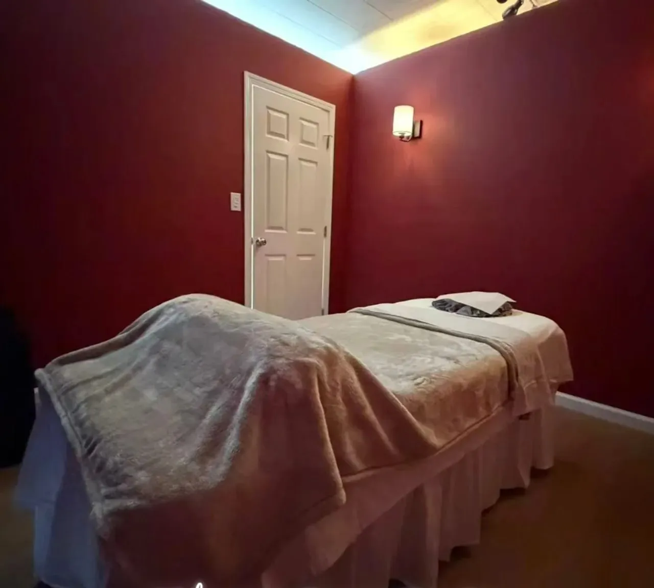 A single treatment room at Organic Day Spa, with the massage table made up against a deep red wall